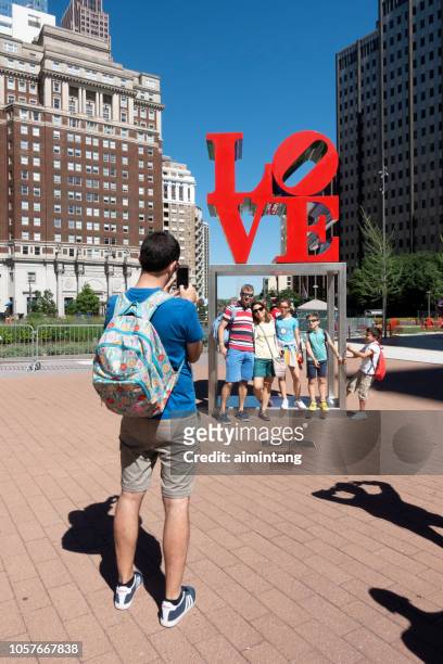 a man taking pictures for a family at love park in downtown philadelphia - john f kennedy plaza philadelphia stock pictures, royalty-free photos & images
