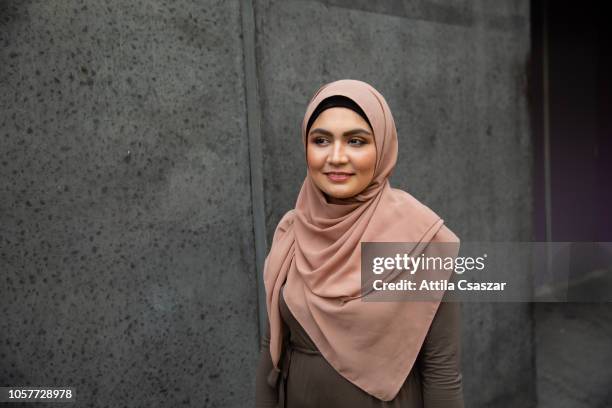 portrait of a smiling young woman wearing hijab on street - arab community life stock-fotos und bilder