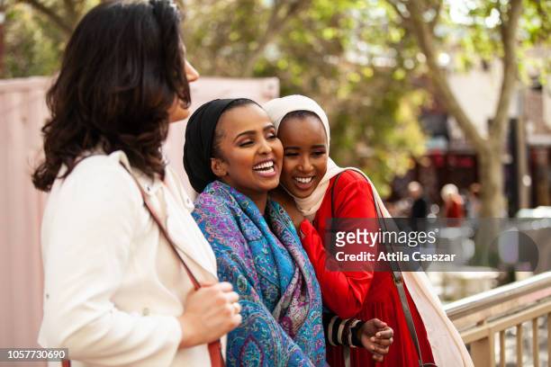 happy female friends standing and laughing on street in city - perth street stock pictures, royalty-free photos & images