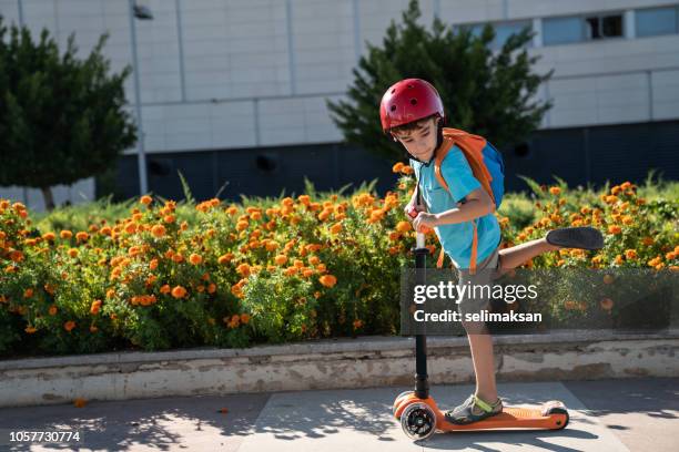 petit garçon à l’aide de push scooter dans le parc public - enfant cartable photos et images de collection