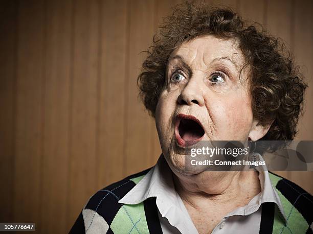 studio portrait of shocked senior woman - boca abierta fotografías e imágenes de stock