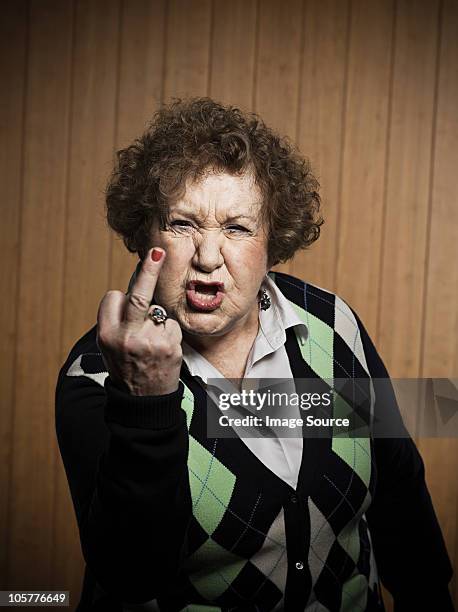 senior woman making obscene gesture - doigt dhonneur stockfoto's en -beelden