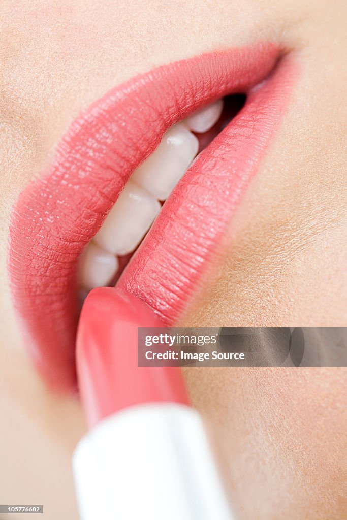 Young woman applying lipstick