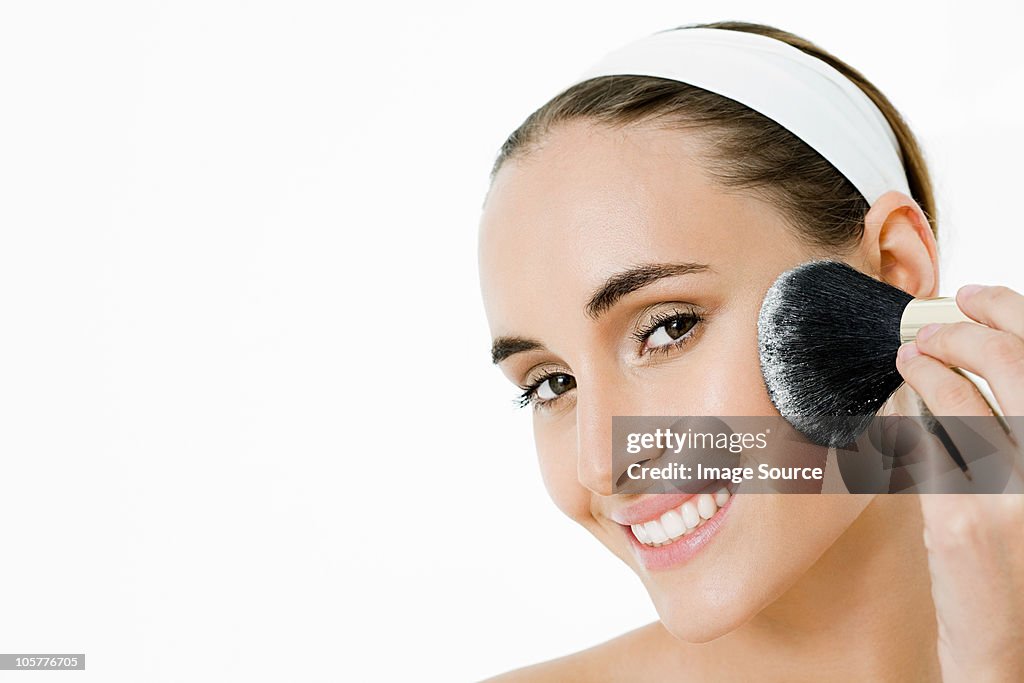 Young woman applying blusher
