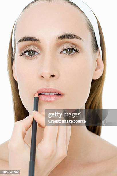 young woman applying lip liner - lip liner stock pictures, royalty-free photos & images