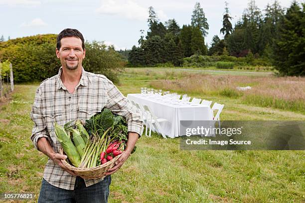 man in field with basket of produce and table in background - cruciferae stockfoto's en -beelden