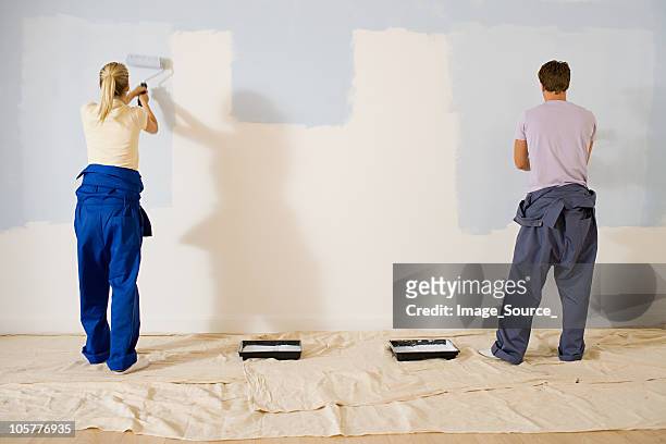 giovane coppia dipinto una parete - muro casa foto e immagini stock