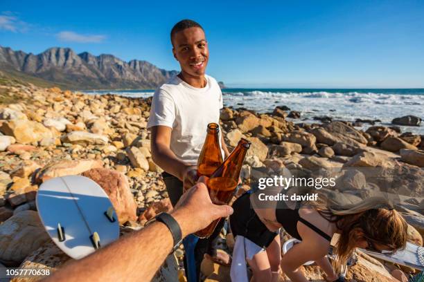 pov of men toasting with beers after a surf together - african pov stock pictures, royalty-free photos & images