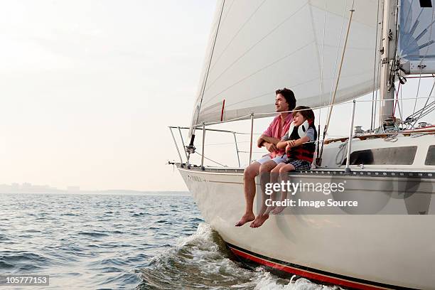 father and son sitting on yacht - father son sailing stock-fotos und bilder