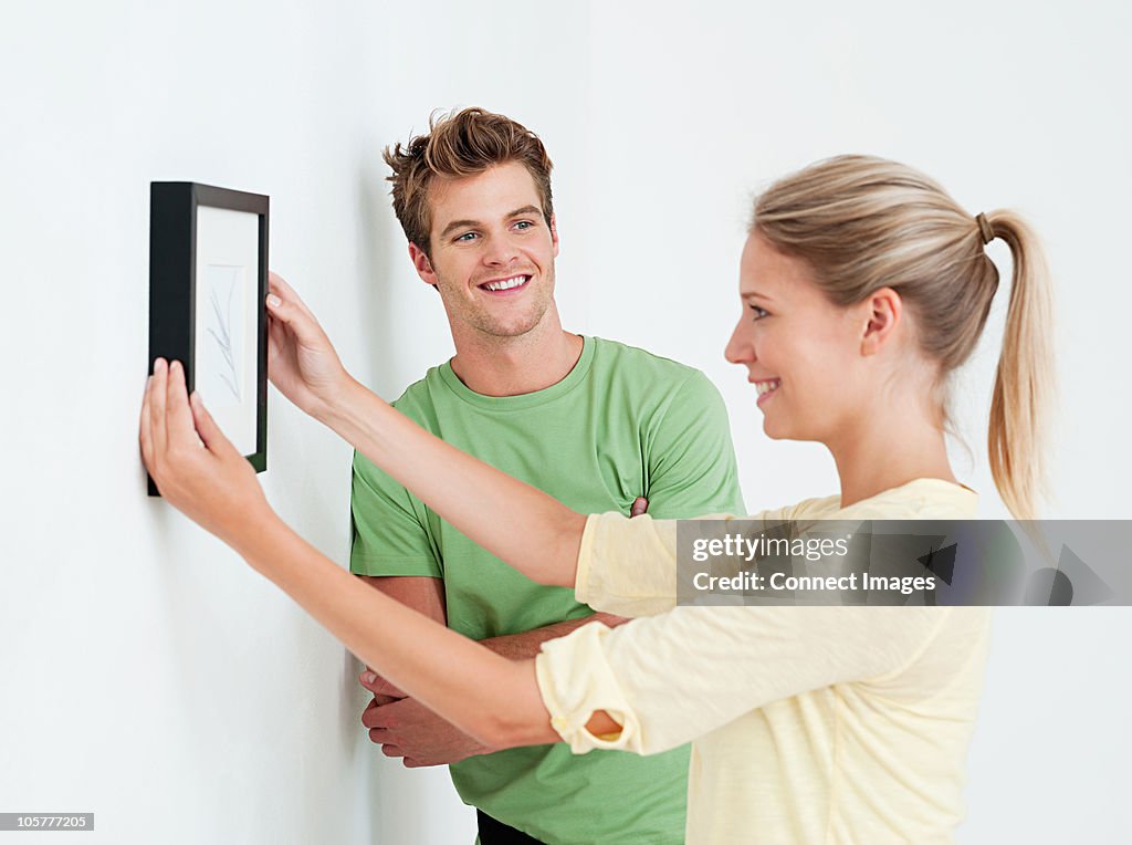 Young couple hanging a picture