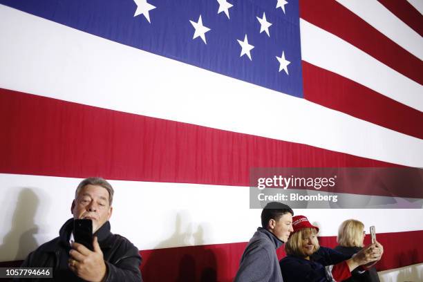 Attendees take selfies in front of an American flag before the start of a campaign rally for Mike Braun, Republican U.S. Senate candidate from...
