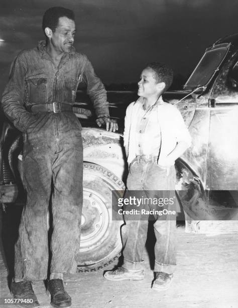 American stock car racing driver, Wendell Scott poses with his young son at a Modified race, 1955.