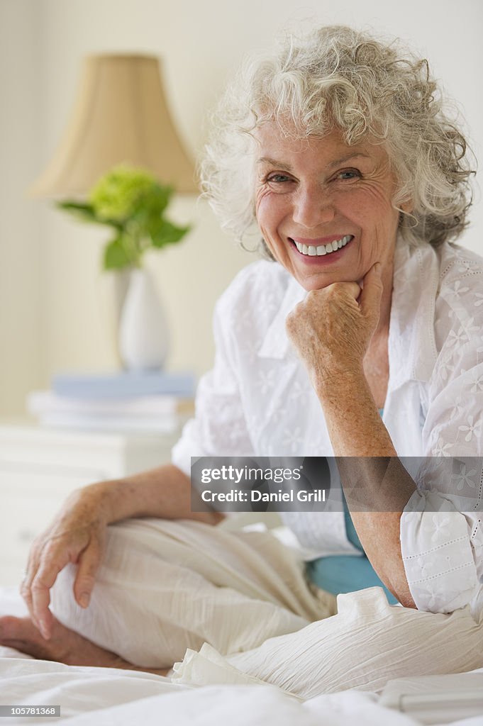 Portrait of a gray haired woman sitting on bed