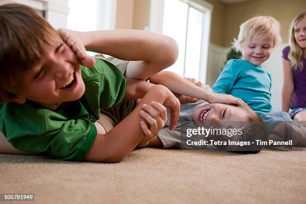 children play fighting on floor - rough housing stock pictures, royalty-free photos & images