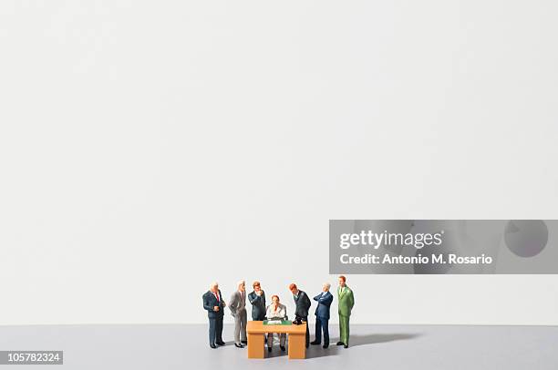 figurines of people standing around desk - miniature stockfoto's en -beelden