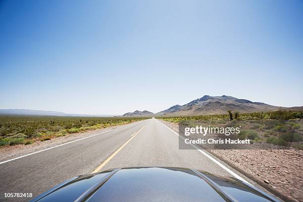 car driving on highway through the desert - capô de carro imagens e fotografias de stock