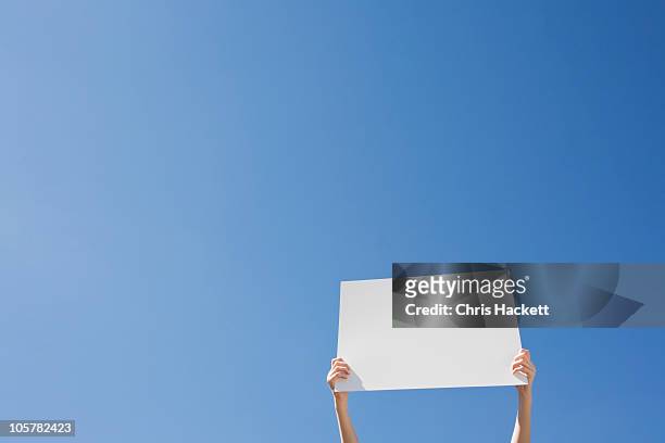 arms holding a blank placard - placard stockfoto's en -beelden