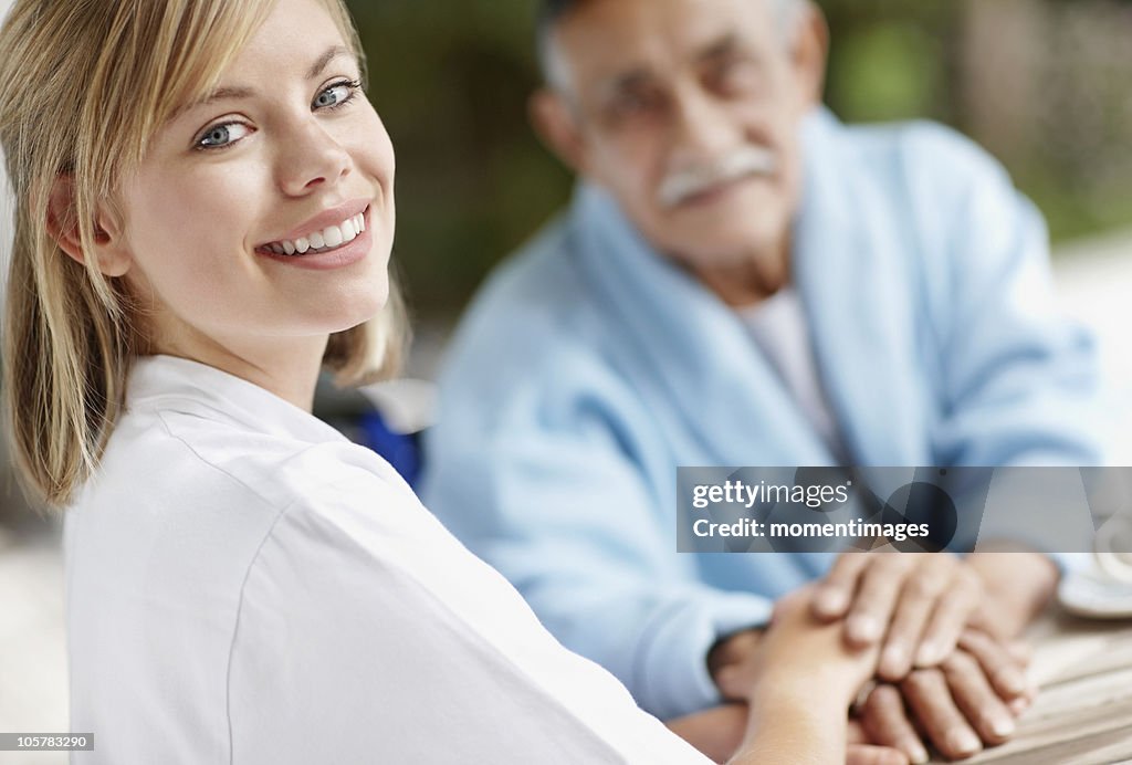 Nurse and senior man holding hands