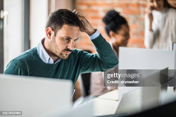 young worried businessman working on laptop at corporate office. - confusão imagens e fotografias de stock