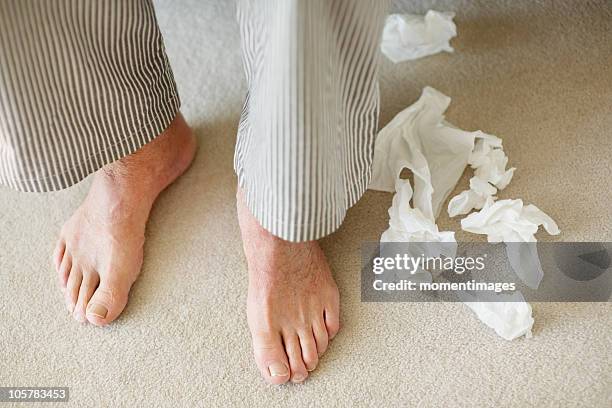 man's feet surrounded by crumpled tissues - papiertaschentuch stock-fotos und bilder
