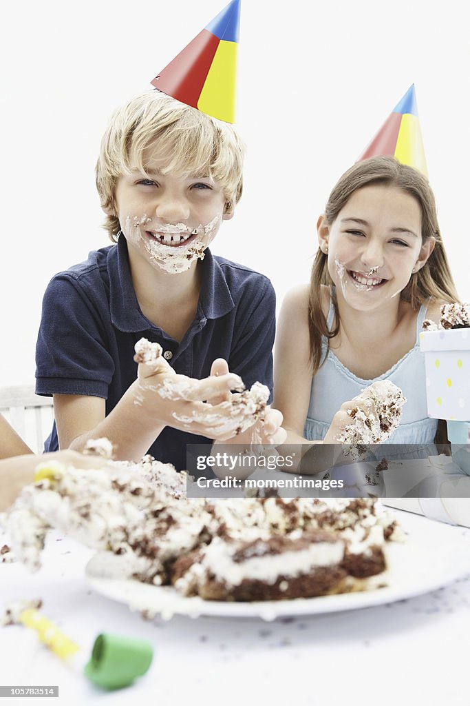 Children eating birthday cake with their hands