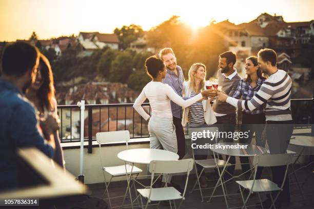 felici colleghi di lavoro che brindano a una festa in terrazza al tramonto. - patio party foto e immagini stock