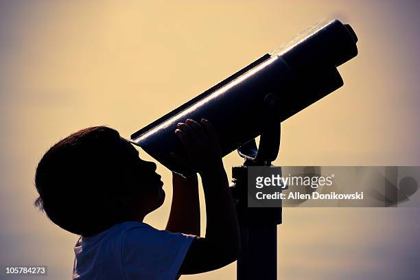 boy looking through telescope at beach - telescopio astronómico fotografías e imágenes de stock
