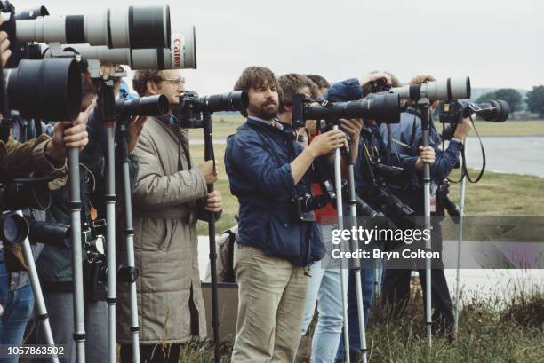 Press photographers with cameras and telephoto lenses, stand on the tarmac at Aberdeen airport as they await the arrival of the Royal flight carrying...