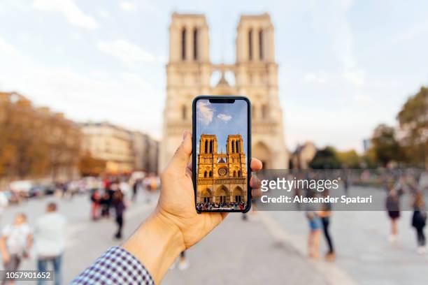 tourist taking picture of notre dame cathedral with smart phone, personal perspective view - augmented reality phone stock-fotos und bilder