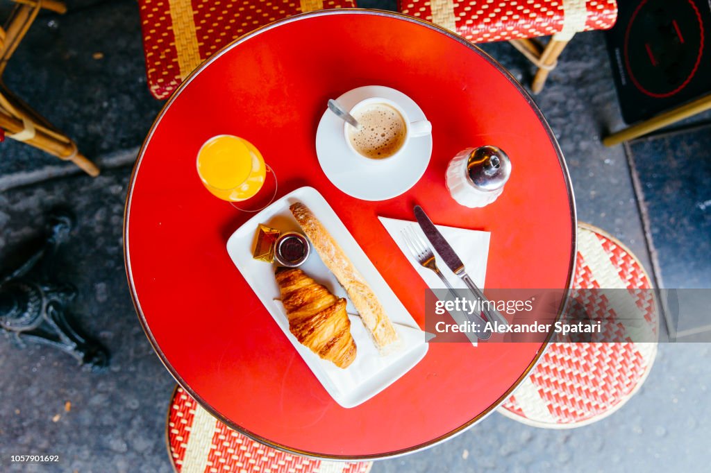 French breakfast with fresh croissant, baguette bread, coffee and orange juice served in cafe, high angle view