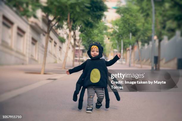 happy baby boy running dressed as a spider - fancy dress costume 個照片及圖片檔