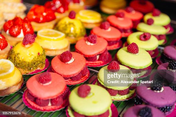pastries display in patisserie shop in paris, france - kokosmakroon stockfoto's en -beelden