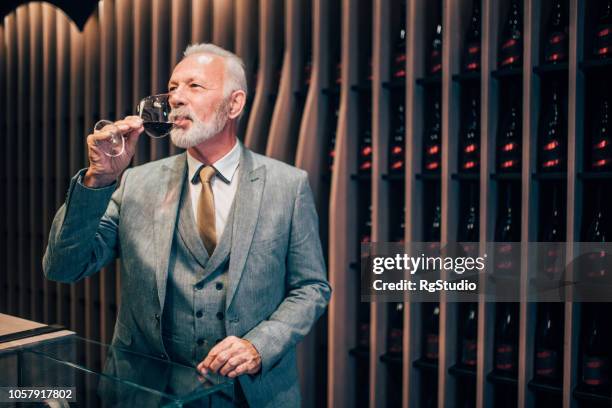 oude man smakende rode wijn - wijn proeven stockfoto's en -beelden