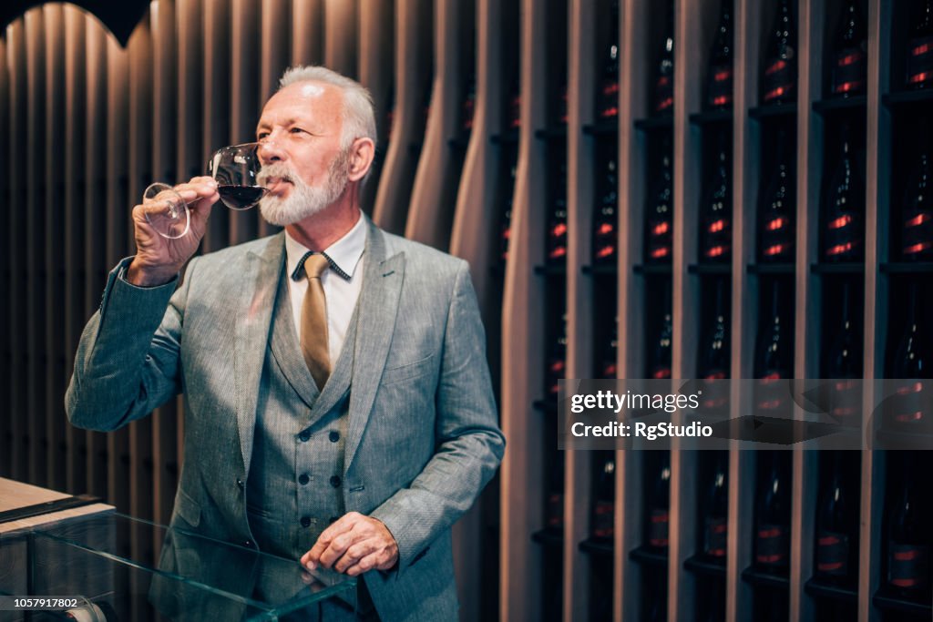 Old man tasting red wine