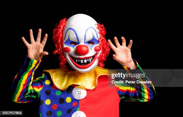 young boy scaring people wearing clown mask - clown stockfoto's en -beelden