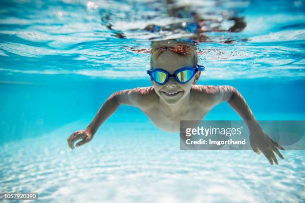 cute little boy swimming underwater in pool - boy swimming stock pictures, royalty-free photos & images