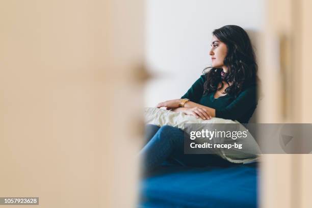 lonely young woman sitting alone in room - loneliness teenager stock pictures, royalty-free photos & images