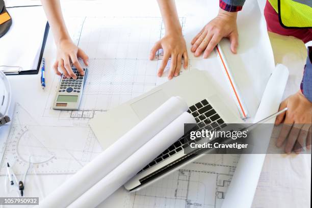 macro of hands on blueprints with architect making floor plans using computer and graph tools"n - construction contract stock pictures, royalty-free photos & images