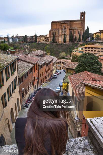 woman looking at the basilica di san domenico in siena, tuscany, italy - siena italy stock pictures, royalty-free photos & images