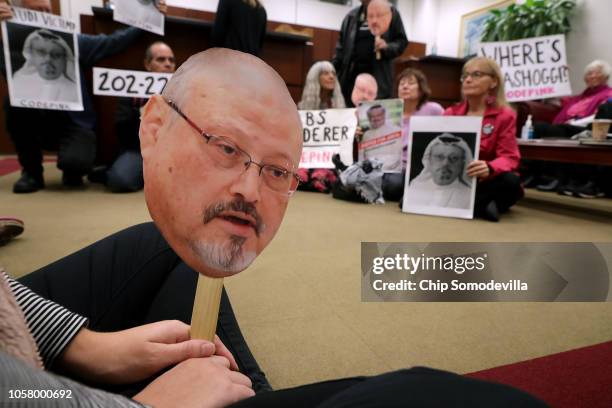 About 17 protesters from Code Pink: Women for Peace hold paper masks of Saudi dissident and Washington Post columnist Jamal Khashoggi while...