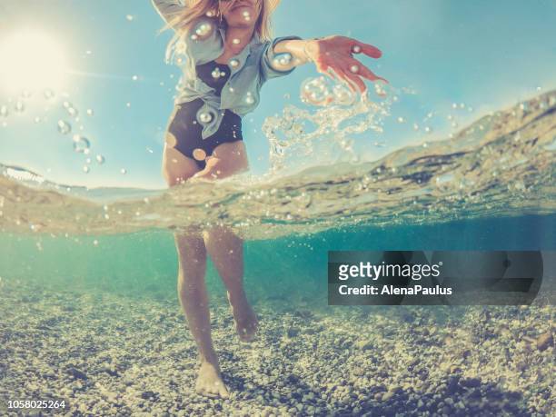 giovane donna giocosa nel mare di spalato, metà sott'acqua metà sopra - half underwater foto e immagini stock