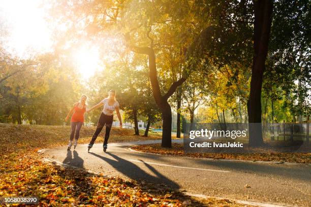 skeeleren voor jonge vrouwen in het park bij zonsondergang - skaten stockfoto's en -beelden