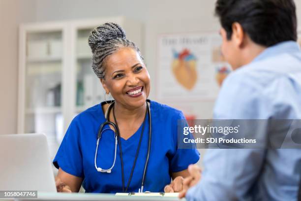 cheerful nurse laughs with unrecognizable patient - nurses laughing stock pictures, royalty-free photos & images
