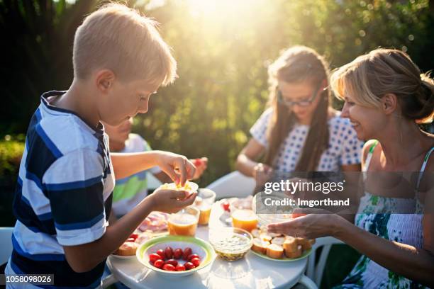 family eating fresh breakfast outdoors - child eating outdoors stock pictures, royalty-free photos & images