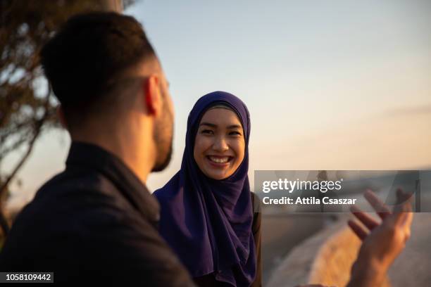 woman wearing hijab talking with friend at beach at sunset - australian community stock-fotos und bilder