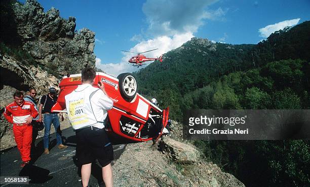 Tommi Makinen looks at the wreckage of his car as it lies on the edge of the road follwoing a crash during the Rally of Corsica, a part of the World...