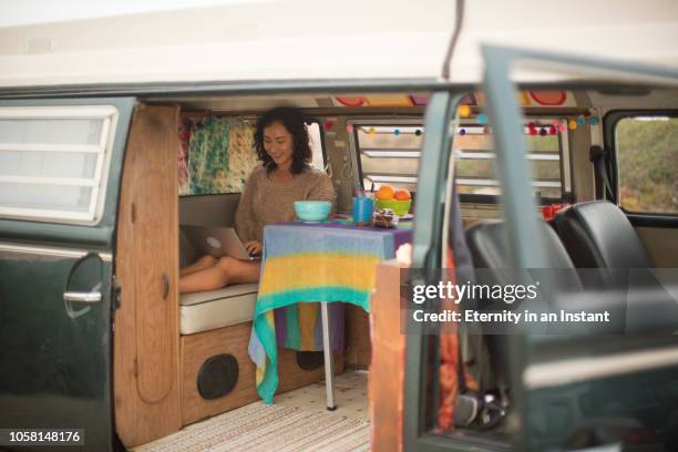 young asian woman sitting in her camper van working on a laptop - wonderlust computer stock pictures, royalty-free photos & images