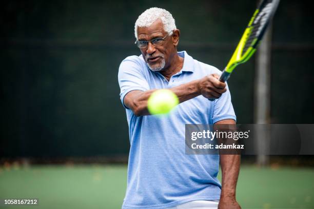 senior black man playing tennis - tennis game stock pictures, royalty-free photos & images