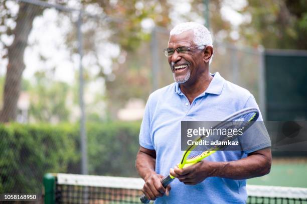 uomo nero senior che gioca a tennis - anziani attivi foto e immagini stock