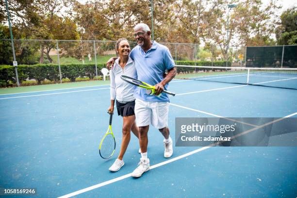 senior black couple walking off the tennis court - play off stock pictures, royalty-free photos & images